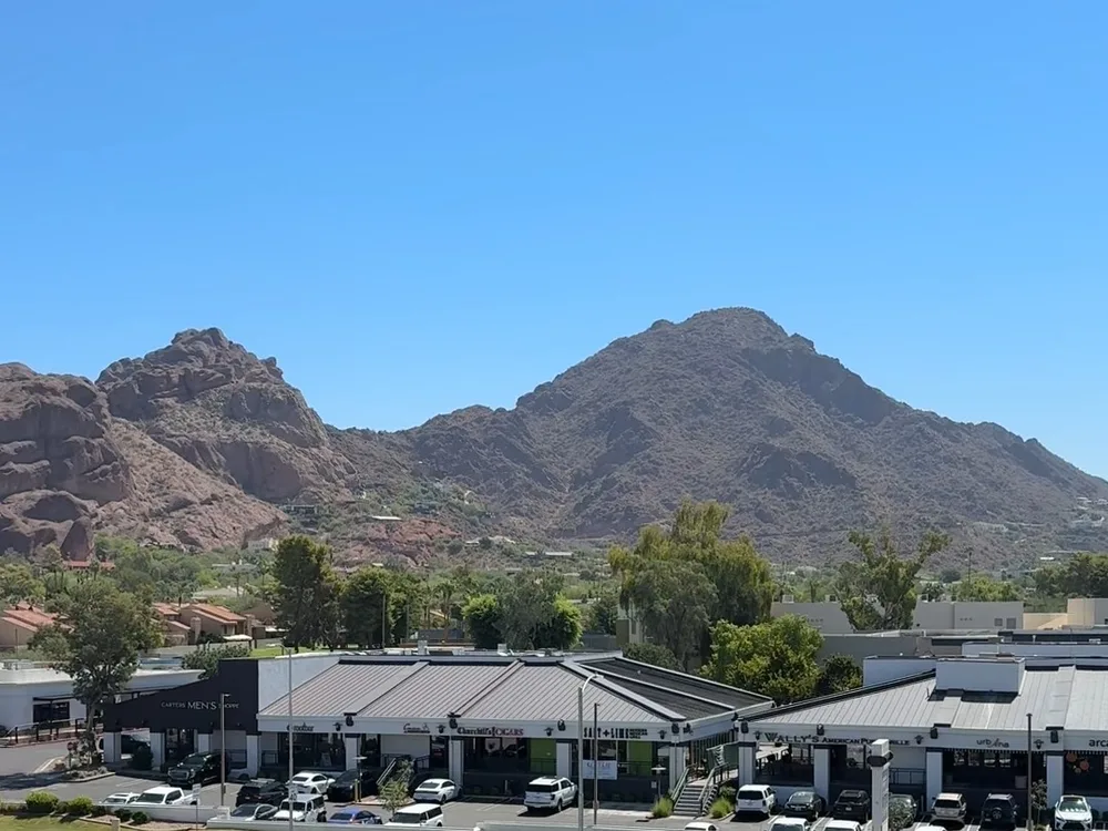 Camelback Mountain rising above trees and rooftops under a clear blue sky