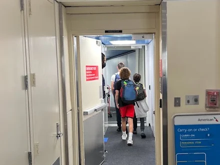 Three of our kids walking down a jet bridge to board a plane at gate D23