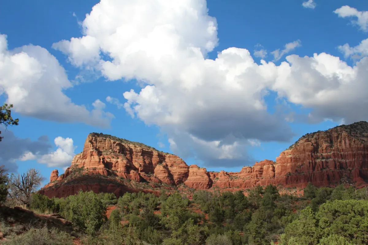Sedona's red rock formations under a bright blue sky with big white clouds