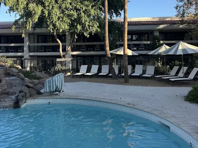 The pool at The Scott in Scottsdale with striped umbrellas, lounge chairs, and a rock waterfall