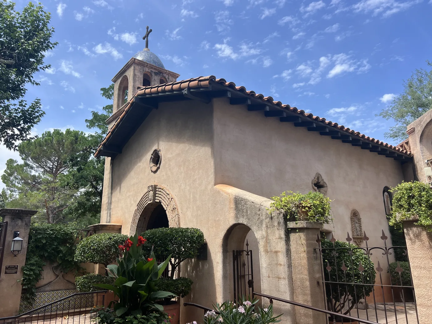 The Tlaquepaque chapel in Sedona with a tile roof, bell tower, and cross against a blue sky
