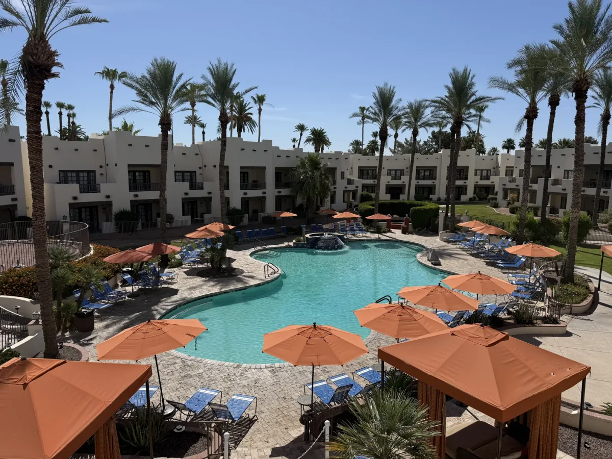 The main pool at The Wigwam in Litchfield Park, ringed by palm trees and orange umbrellas